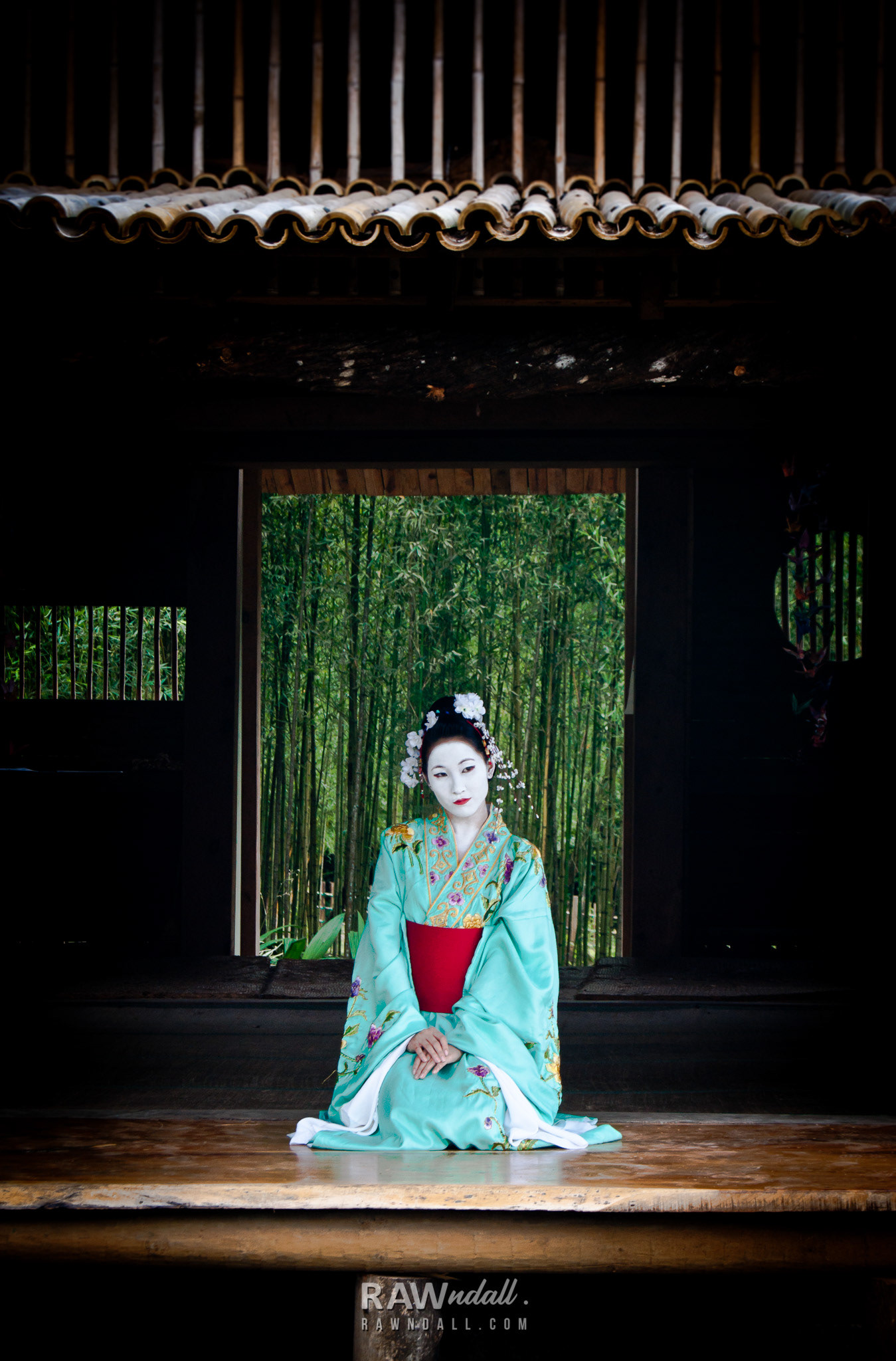 Mujer con traje de geisha en casa típica japonesa.